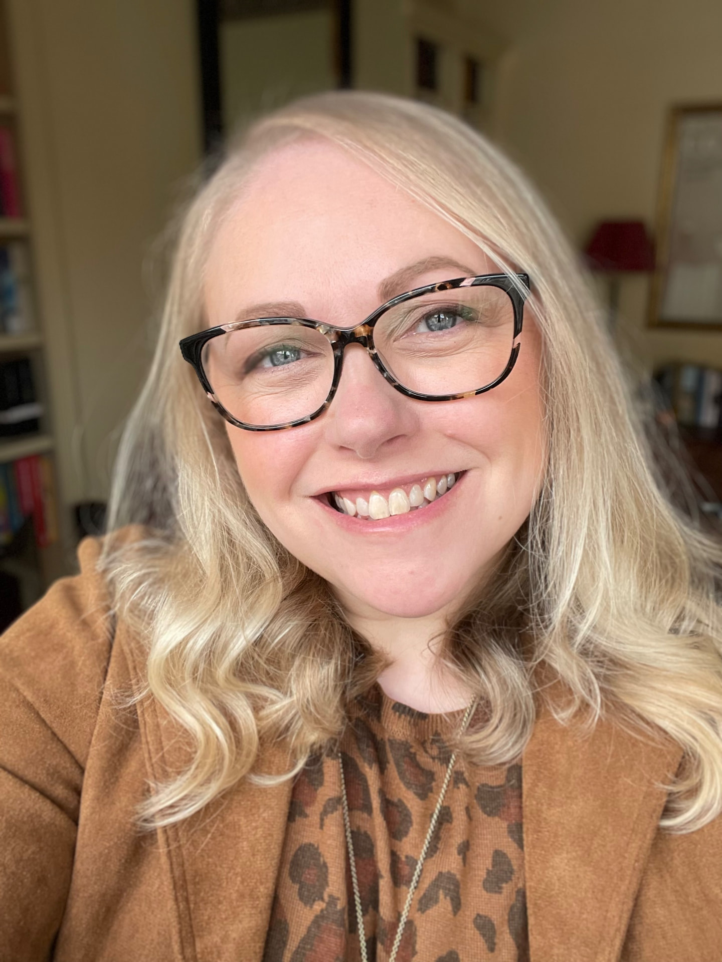 Tor, host of Bookshelf Friends, smiling in front of a bookshelf